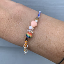 Load image into Gallery viewer, purple, luster white and yellow with red stripes seed bead bracelet with iridescent, shell, peach heart and sterling silver stardust beads with a sterling silver peace sign charm