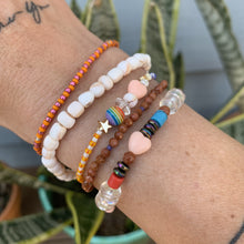 Load image into Gallery viewer, purple, luster white and yellow with red stripes seed bead bracelet with iridescent, shell, peach heart and sterling silver stardust beads with a sterling silver peace sign charm