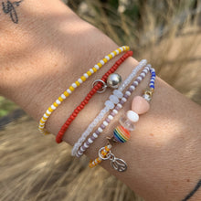 Load image into Gallery viewer, purple, luster white and yellow with red stripes seed bead bracelet with iridescent, shell, peach heart and sterling silver stardust beads with a sterling silver peace sign charm

