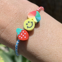 Load image into Gallery viewer, blue, white and red patterned seed bead bracelet with a strawberry, smiley face and multi colored heart bead
