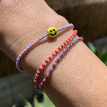 Load image into Gallery viewer, red, blue, white striped seed bead bracelet with a yellow smiley face bead
