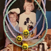 Load image into Gallery viewer, red, blue, green, white striped seed bead bracelet with a yellow smiley face bead
