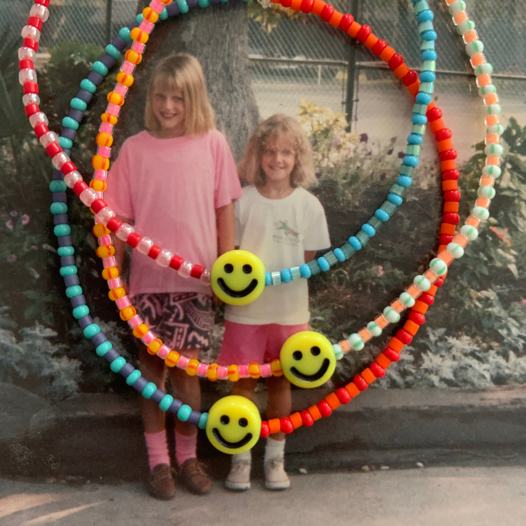 multi colored and patterned seed bead bracelet with a yellow smiley face bead
