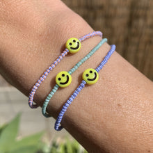 Load image into Gallery viewer, red, blue, green, white striped seed bead bracelet with a yellow smiley face bead
