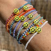 Load image into Gallery viewer, multi colored red, blue, green, white striped seed bead bracelet with a yellow smiley face bead
