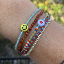 Load image into Gallery viewer, red, blue, green, white striped seed bead bracelet with a yellow smiley face bead
