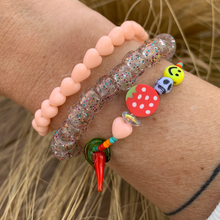 Load image into Gallery viewer, red, orange and turquoise seed bead bracelet with a peach heart, round strawberry, skull, smiley and a glass chili pepper and peach heart and glitter bracelets
